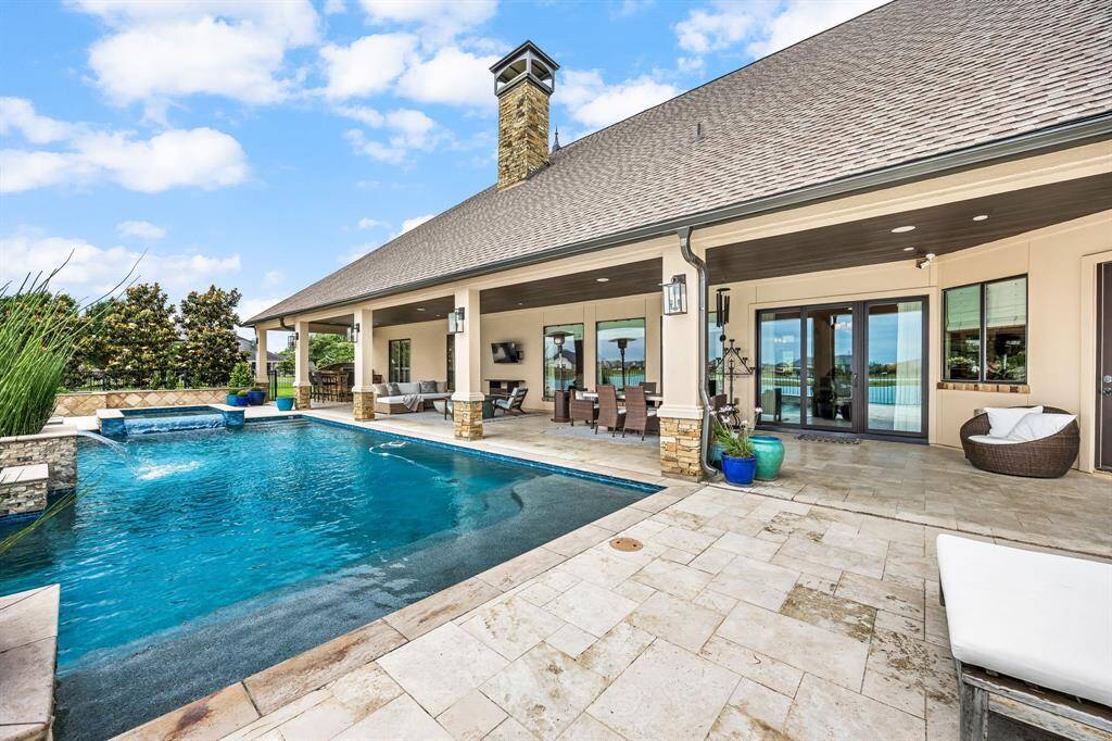 Enjoy a luxurious outdoor area with a spacious swimming pool and a hot tub. The covered patio features elegant stone pillars, ample seating, and a dining area, ideal for relaxation and entertainment. The surrounding landscape provides a sense of privacy and tranquility.