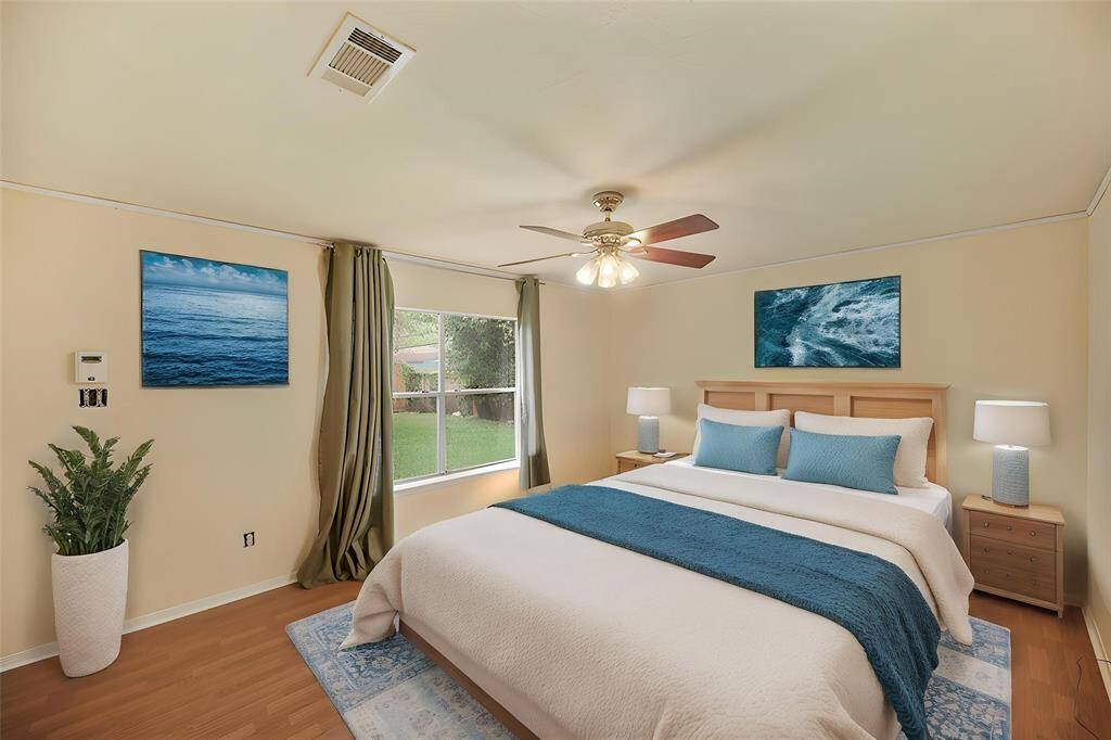 Virtually Staged: Primary bedroom with wood floors, a large window, and a ceiling fan.