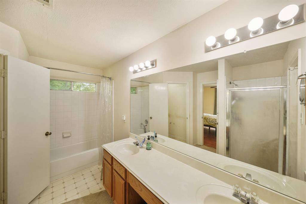 The primary bath has double sinks, a wooden vanity, a large mirror, a soaking tub, and walk-in shower.