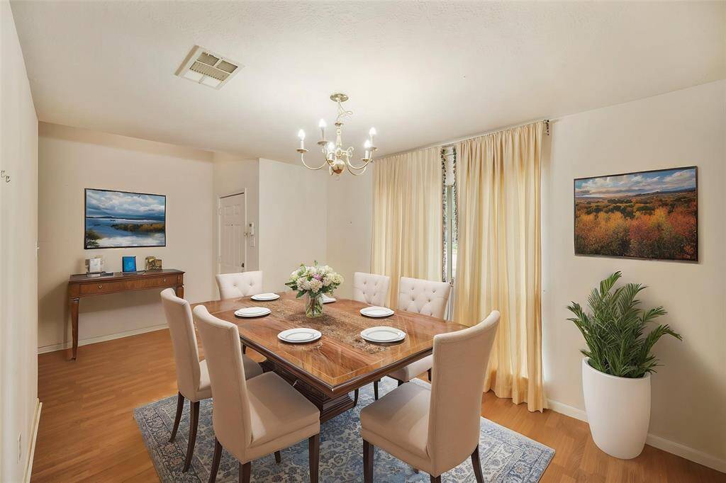 Virtually Staged: Nestled in the front of the house is this dining room with pendant lighting, wood floors, and a large window.