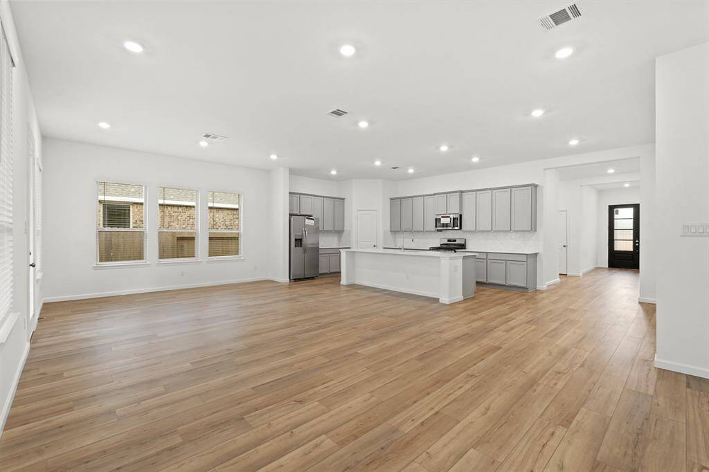 Luxurious Living Room with hardwood flooring, recessed lighting and tons of space to utilize when spending time with family or friends.