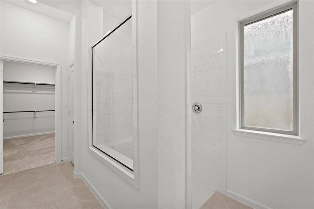 Primary Bathroom Oasis features a walk in shower with framed glass, delicate white tones throughout adding to the elegance, and a HUGE walk in closet for all your wardrobe needs!