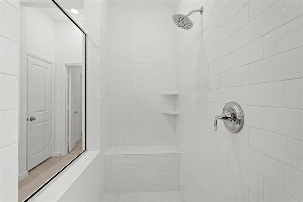 Exquisite Shower to Enjoy with tile surround and flooring, bench and shelving in the Primary Oasis.