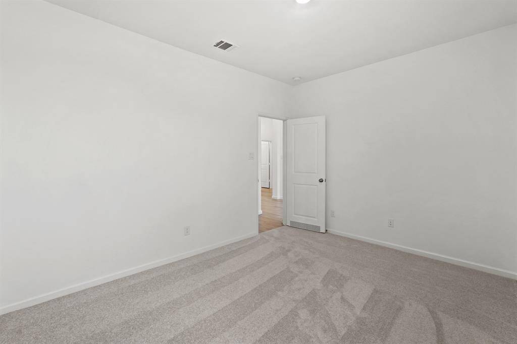 Spacious Secondary Bedroom with plush carpet and lighting.