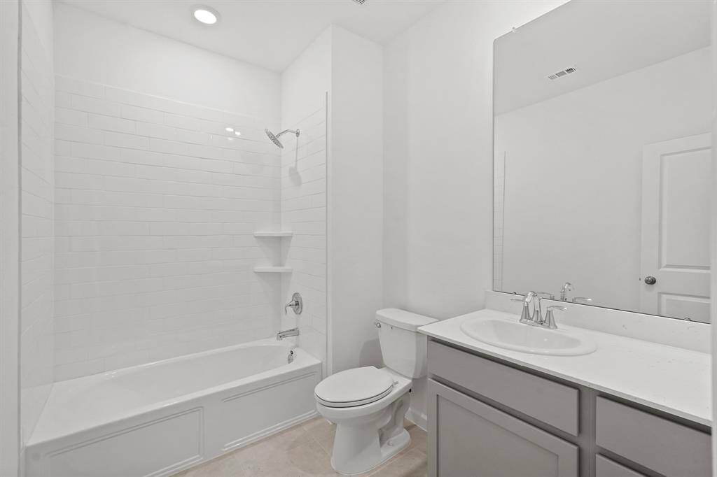 Full Bathroom with grey tone cabinetry, extended mirror, tile flooring and tub/shower with tile surround.