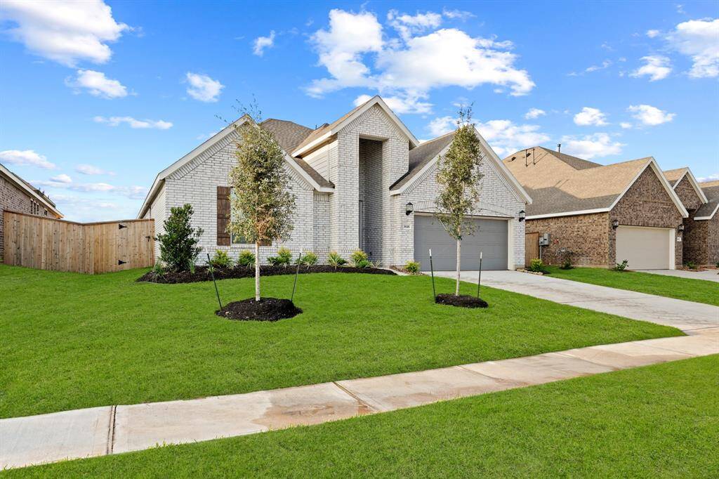Another view of this breathtaking home and gorgeous greenspace offered in the front yard, trees, and walkway.