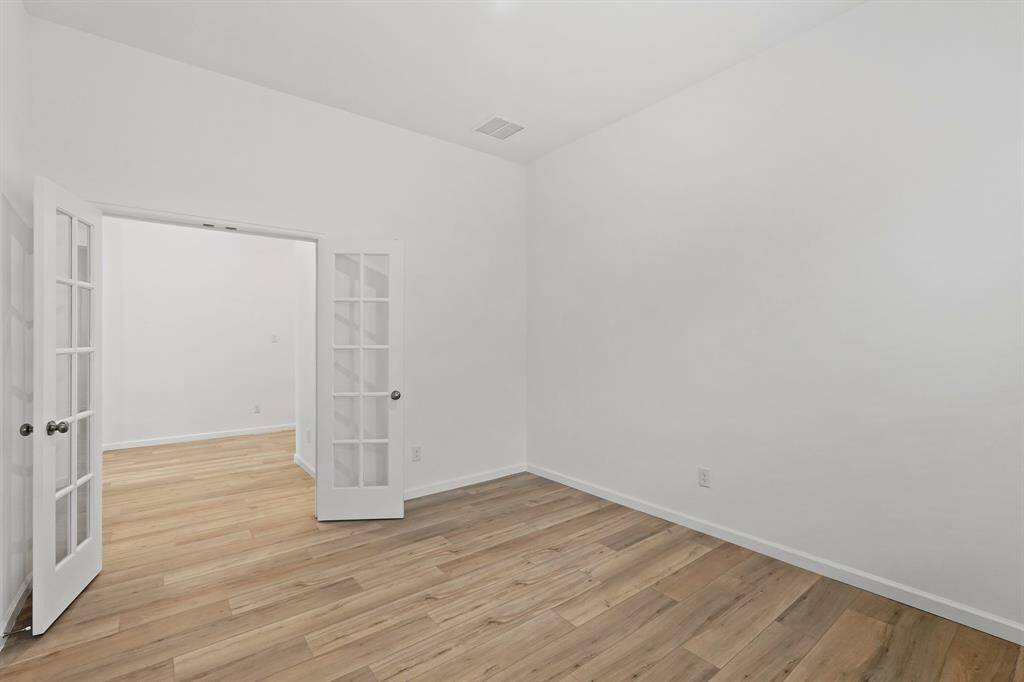 Sophisticated Study through the French Doors with glass offering hardwood flooring and tons of space to work in privacy.