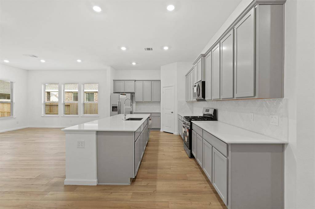 Another view of the Gourmet Kitchen with gorgeous grey cabinetry, custom tile backsplash and pantry for food storage.