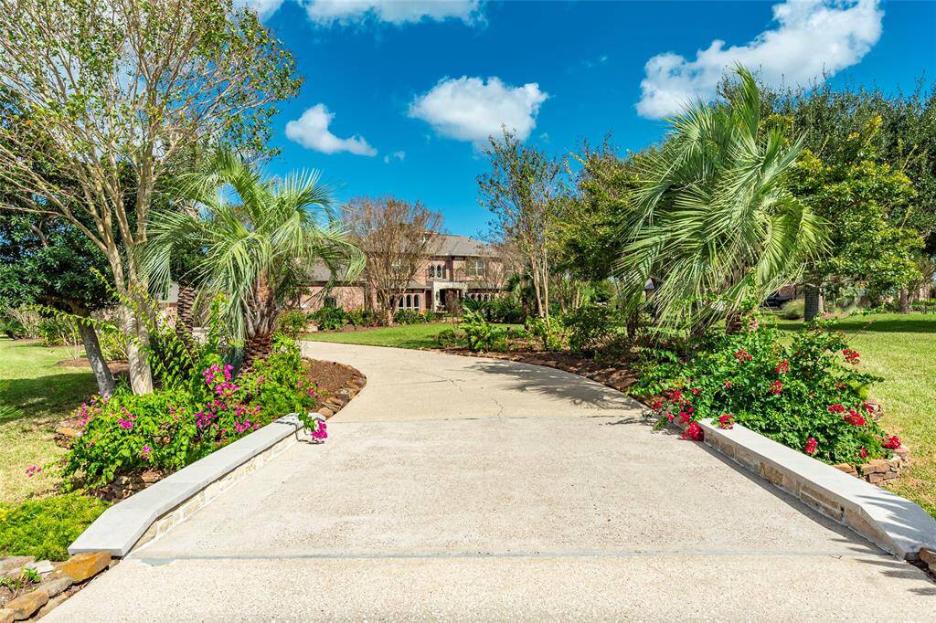 A winding extended driveway, accented with recently added rock-lined culverts and lush tropical landscaping, creates a grand approach to the home. Thoughtfully set back, with exceptional privacy and curb appeal, offering a serene retreat tucked away.