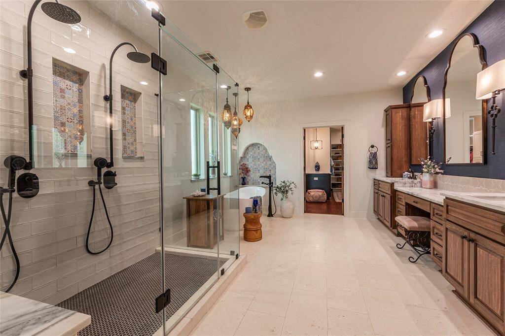Step into luxury in this beautifully renovated primary bathroom (2021), featuring elegant his-and-her sinks with stunning custom mirrors and sophisticated wall-mounted light sconces. The expansive granite countertops offer both beauty and functionality. A dedicated vanity sitting area provides the perfect space for personal care. Every detail has been thoughtfully designed to create a serene and stylish retreat.