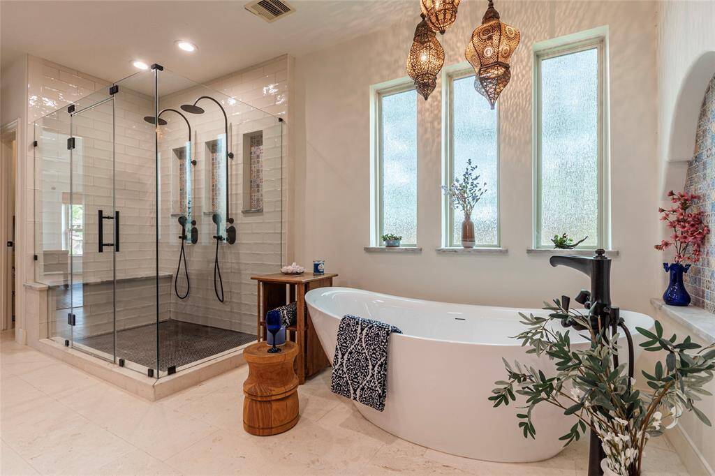 The expansive primary suite is complemented by a beautifully renovated spa-like bathroom, completed in 2021. This stunning transformation features a seamless glass walk-in shower with dual showerheads, a luxurious freestanding soaking tub with an upscale faucet, and designer tile accent walls that complete this thoughtfully designed retreat.