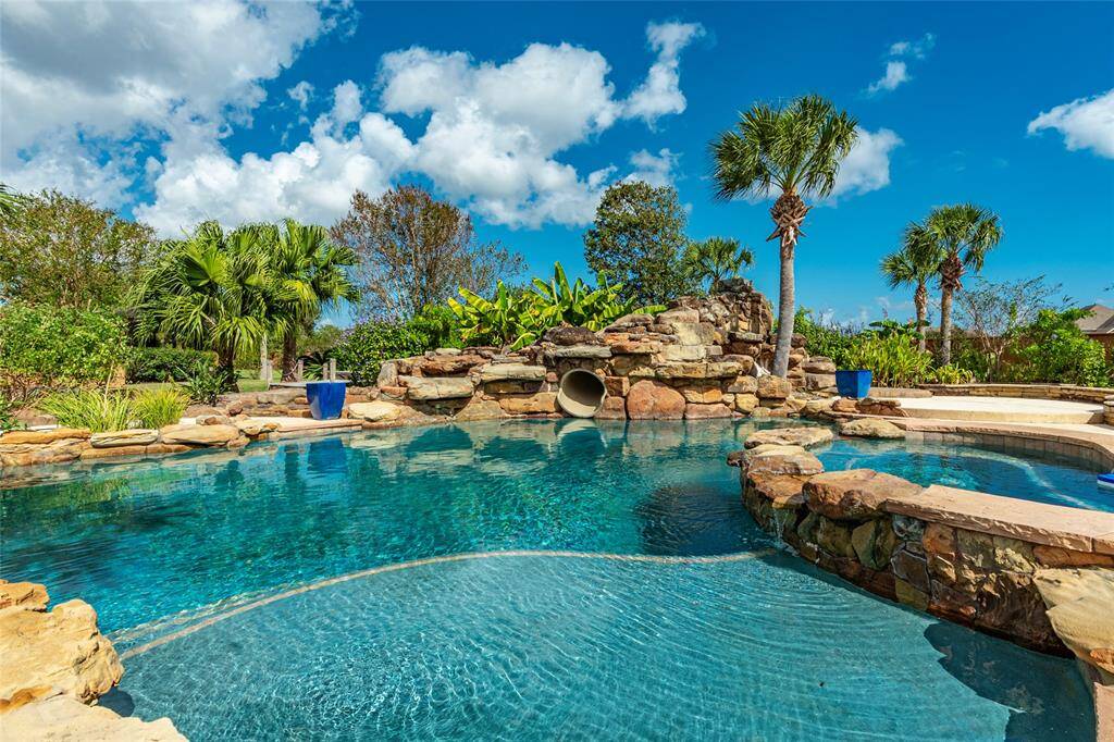 Experience the ultimate in outdoor entertainment with a resort-style heated pool featuring a rock waterslide, cascading waterfall, tanning ledge, and inviting hot tub.
