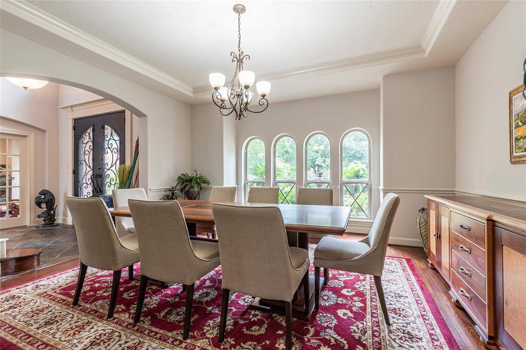 The elegant formal dining room has been freshly painted and offers an inviting layout that flows seamlessly into the grand entryway and butler’s pantry—perfect for both intimate dinners and upscale entertaining. This beautiful room showcases rich wood flooring, arched windows with views of the lush front landscaping, crown and chair-rail molding too.
