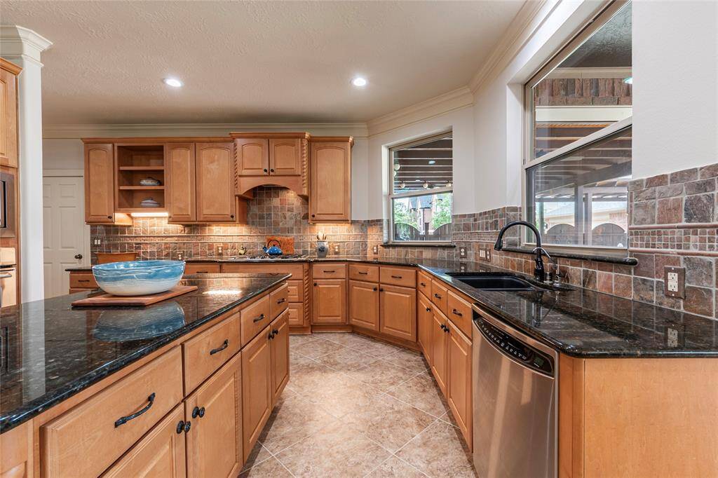 The wood cabinetry with undermount cabinet lighting adds a touch of warmth, while the large double sink and gas cooktop make cooking a breeze. Enjoy pool and backyard views from the kitchen, creating a seamless connection between indoor and outdoor living.