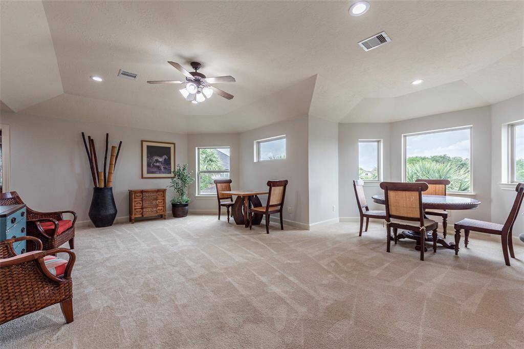 This expansive upstairs entertainment room offers the perfect setting for relaxation and fun, complete with a dedicated game area ideal for a card table, puzzles, or family game night. Large windows frame picturesque views of the backyard and glistening pool, creating a bright and inviting atmosphere.