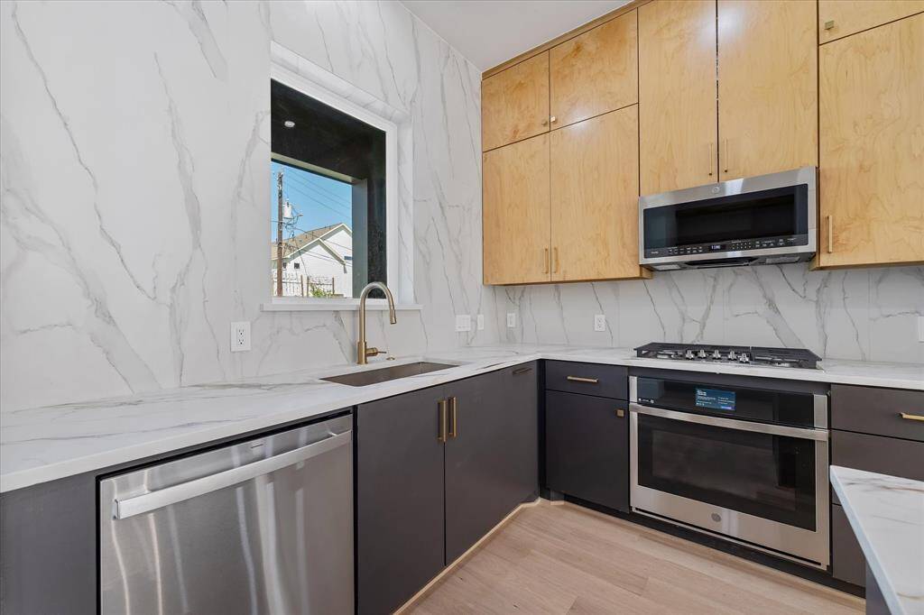 Kitchen: Pictured are GE PROFILE appliances nestled in CUSTOM CABINETRY, with large format tile to the ceiling.