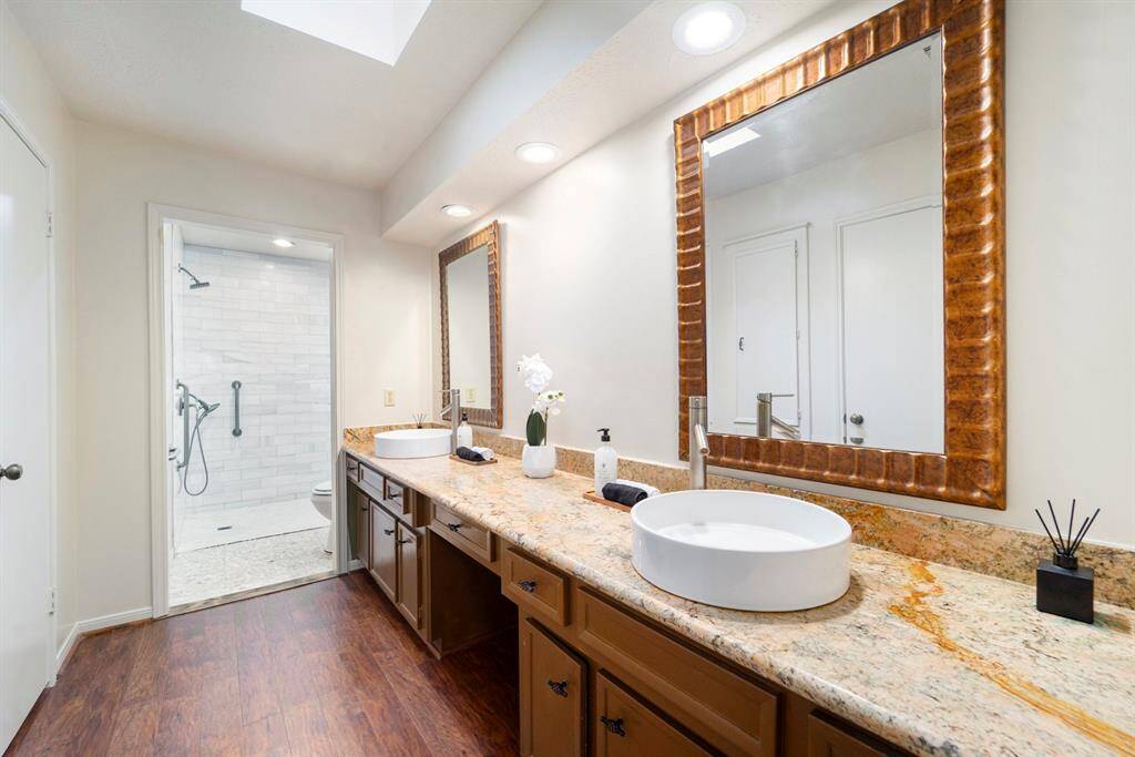 The en-suite bathroom has a spacious feel with dual sinks, plenty of granite counter space, and great lighting.