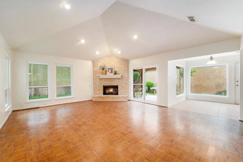 The living room is a bright and inviting space, featuring a cozy corner gas log fireplace that adds warmth and charm without taking up central wall space. a vaulted ceiling enhances the sense of openness, creating an airy and spacious atmosphere.