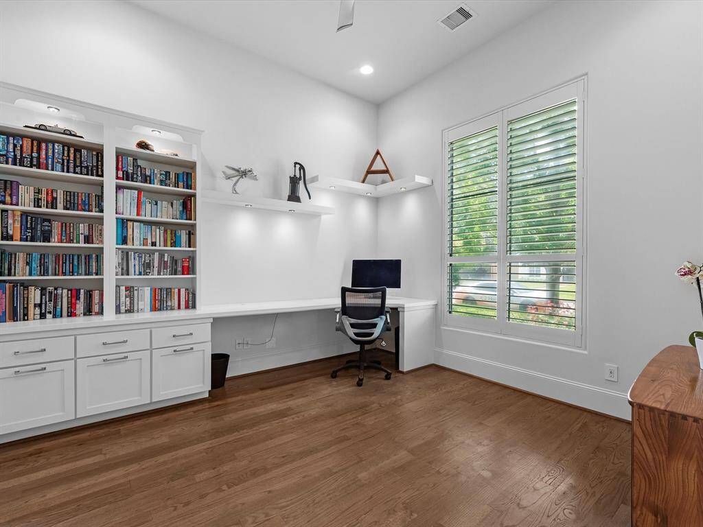 Step into a sophisticated office featuring sleek, modern glass doors that allow natural light to flood the space. The room boasts soaring high ceilings that enhance its spacious and airy feel. Custom built-in cabinets offer ample storage while maintaining a clean, uncluttered aesthetic, making it the perfect blend of style and functionality.