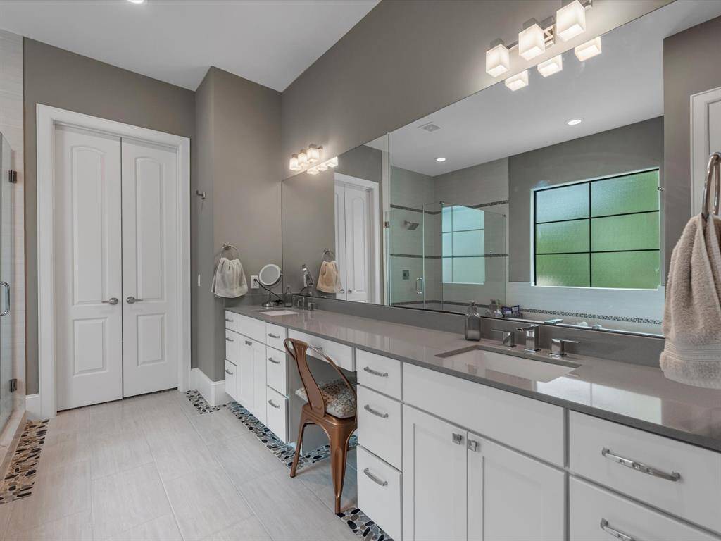 Dual vanities offer ample space, while a chic, expansive mirror enhances the room’s bright and airy feel. Whether you're preparing for the day or winding down at night, this bathroom is the ultimate retreat for relaxation and rejuvenation.