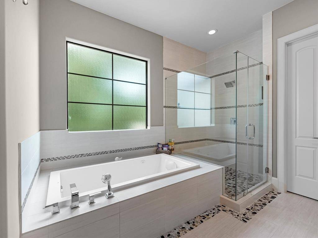 The spacious layout features a stunning freestanding soaking tub, perfect for unwinding after a long day. The walk-in shower boasts sleek glass walls, modern fixtures, and a powerful showerhead, providing a spa-like experience.