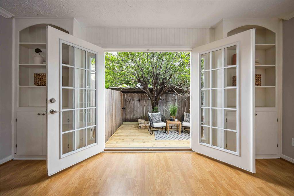 Gorgeous French doors resting between built-in shelving and cabinets lead to a desirable private deck in the back.