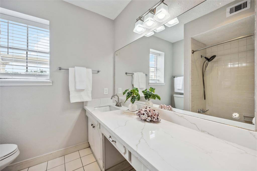 Designed similarly to the primary, the secondary bath features a quartz-topped vanity.