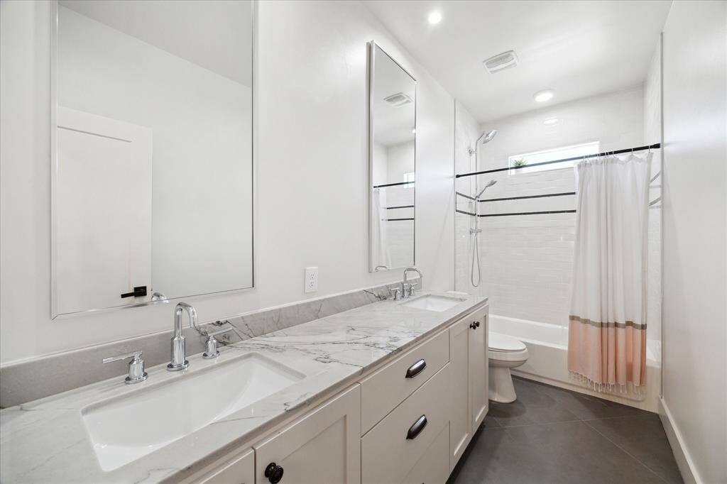 Guest bathroom with dual sinks, plenty of storage, and tub/shower combo.