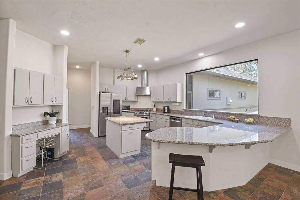The gourmet kitchen boasts ample cabinet space, a center island, breakfast bar & a large window that provides abundant natural light.