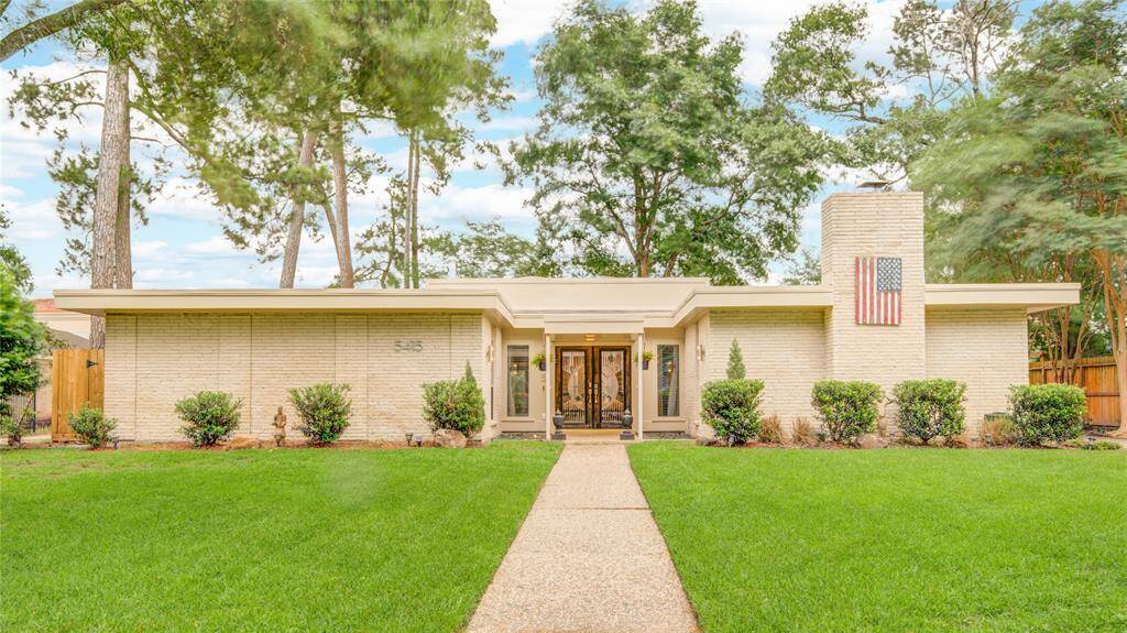 Charming one-story brick home with a welcoming front walkway and manicured lawn nestled beneath mature trees.