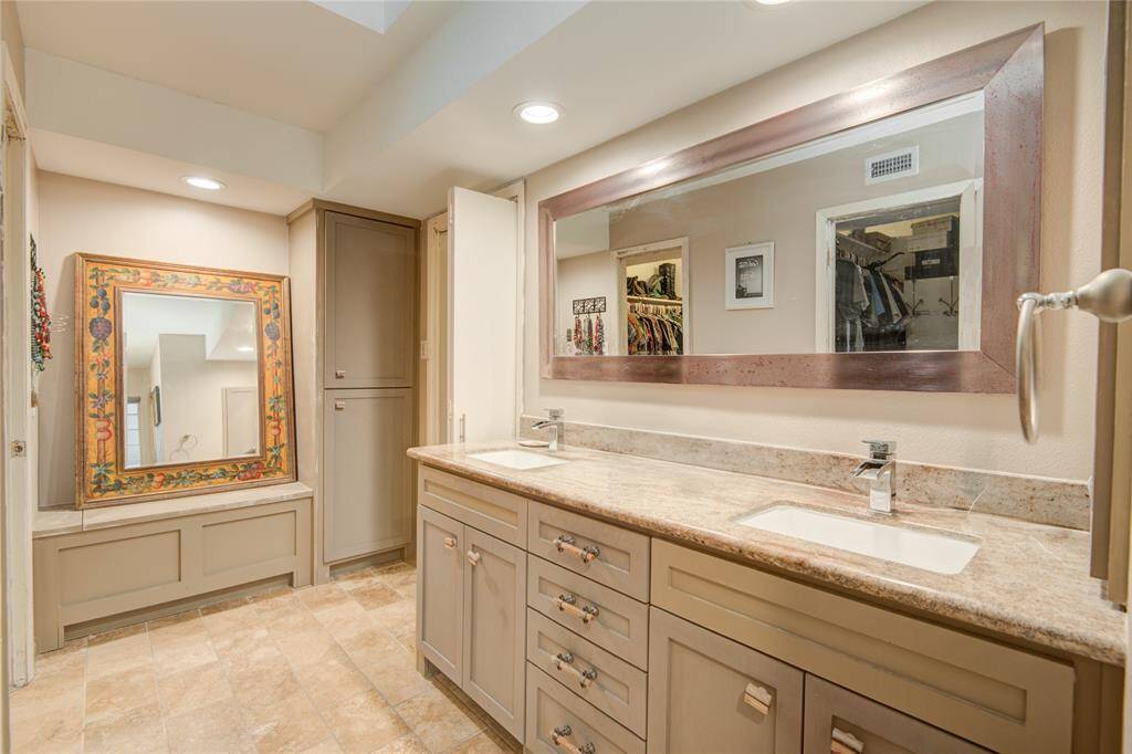 The primary ensuite bath is illuminated by recessed lighting and a tray ceiling, with natural sunlight streaming in for a bright, airy atmosphere.