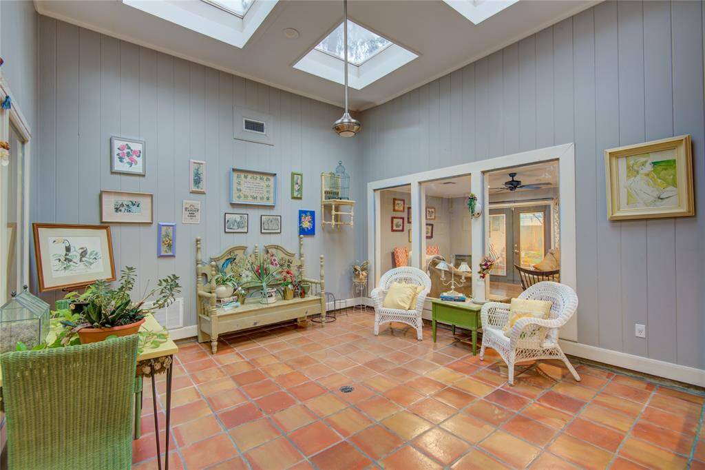 The atrium features multiple skylights above, filling the space with natural light, while Saltillo tile flooring adds warmth and character.