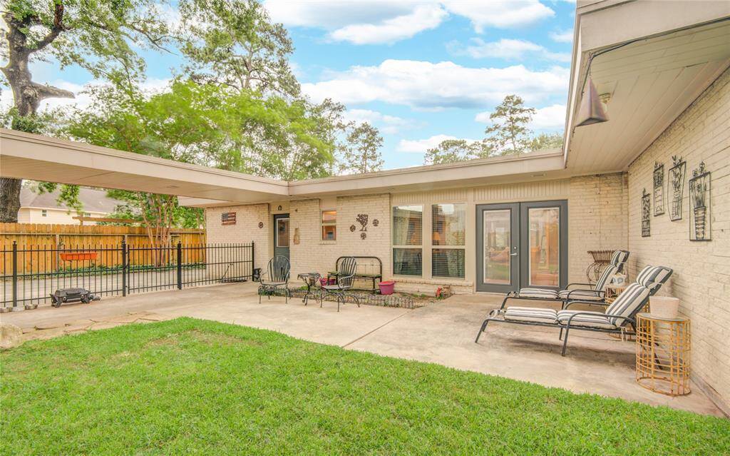 The backyard offers a spacious view of the home’s back and patio, with French doors leading into the family room on the right and an entry door near the driveway providing convenient access to the laundry room leading towards the kitchen.