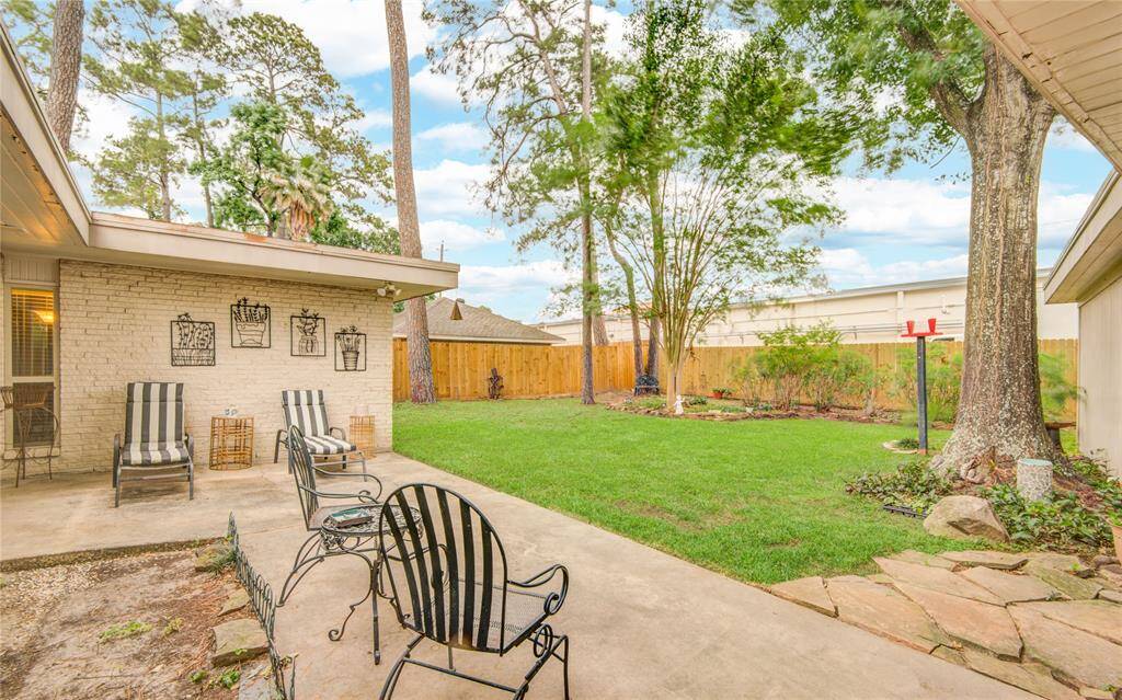 From the back patio, enjoy a serene view of the spacious backyard, framed by mature trees.