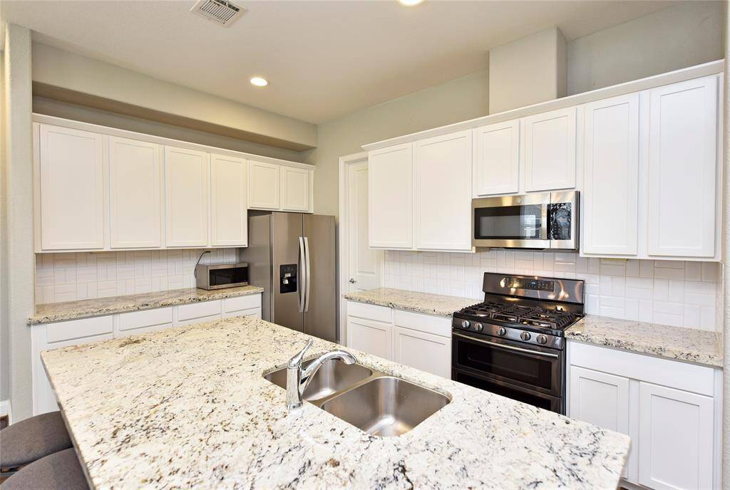 This stunning kitchen features stainless steel appliances, a gas range, built-in microwave, and an abundance of cabinetry for ample storage.