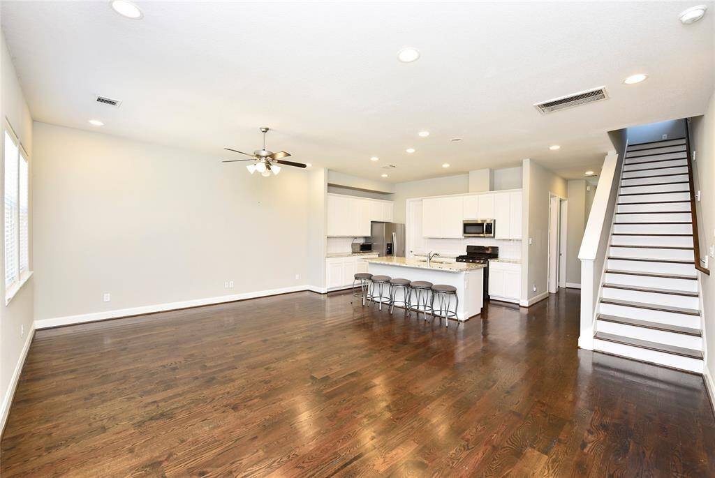 This spacious living room is light and bright, featuring gleaming wood floors and an open layout that flows seamlessly into the kitchen.