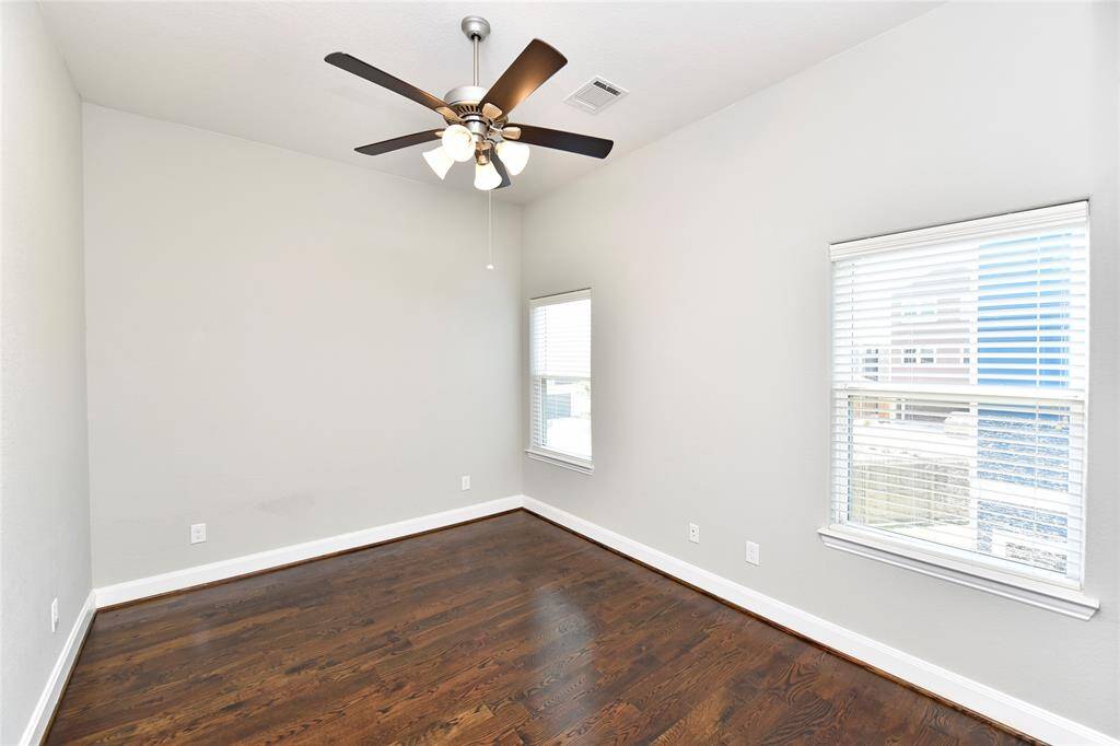The spacious secondary bedroom on the second floor features beautiful wood flooring.