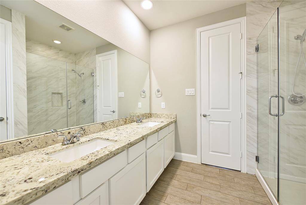 Primary bathroom featuring double sinks, granite countertops, and a stunning oversized shower.