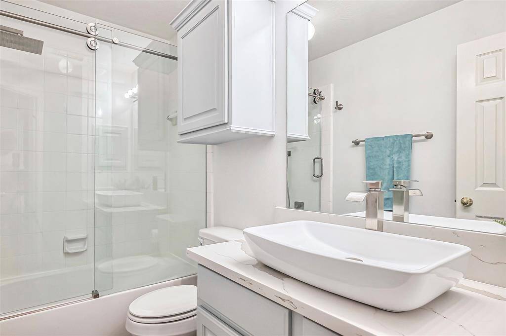 The secondary bath features updated sinks and shower/tub combo with sliding glass doors