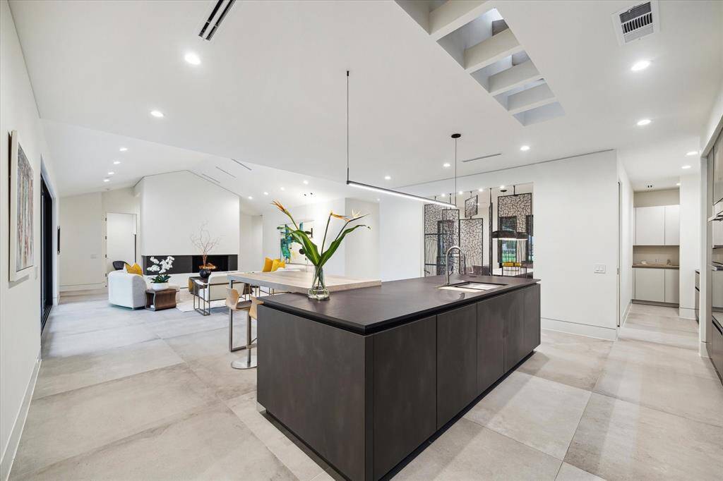 The impressive kitchen island is bathed in natural sunlight from the skylight above, and is complemented by a sleek Thin-Line pendant fixture by SONNEMAN.