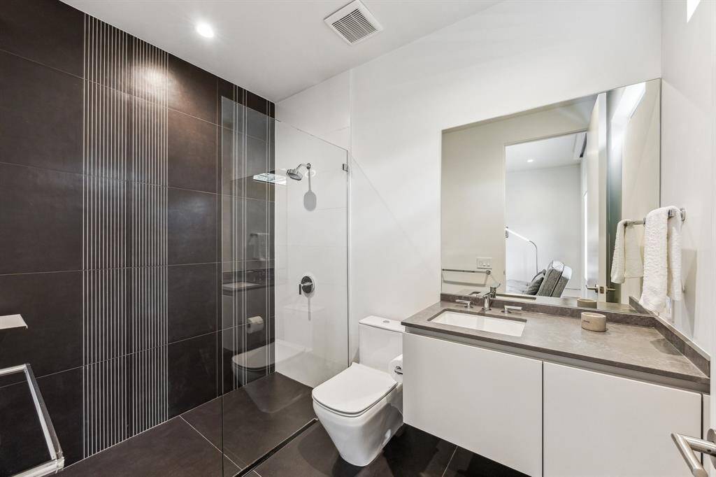 The modern and sleek secondary full-size bathroom features a walk-in shower with wall accent tiles from the CAVA by LucidiPevere Collection and European-style cabinetry by LEICHT, combining functionality with elegant design.