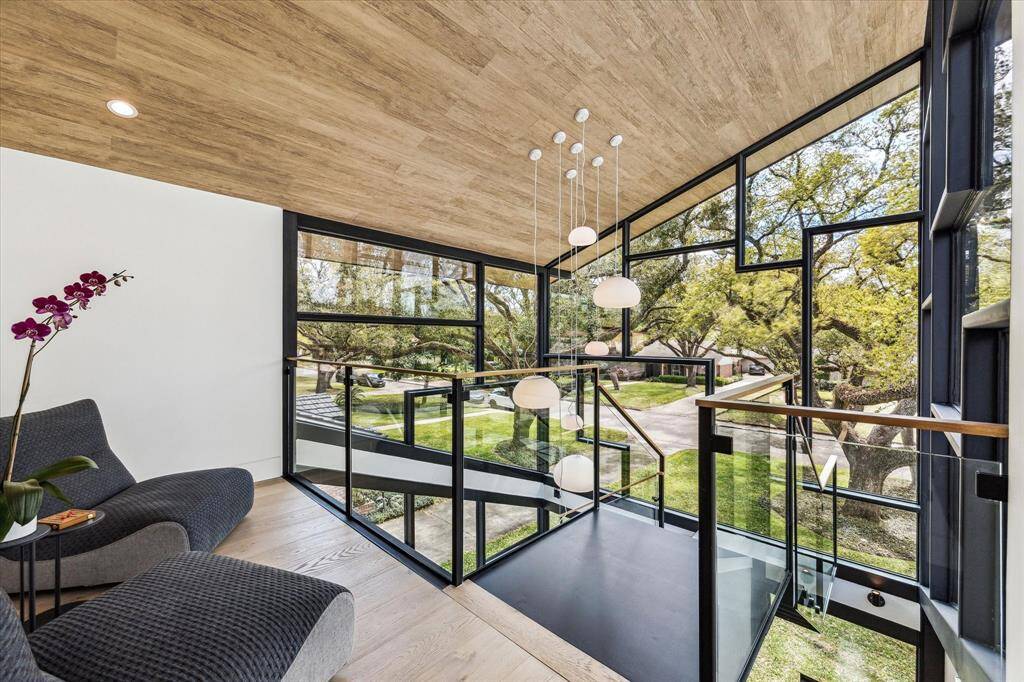 The staircase is a remarkable, custom-crafted piece featuring a unique design with a tempered glass wall. This design offers unobstructed views of the captivating greenery from the yard, adding a touch of nature to the indoor space.