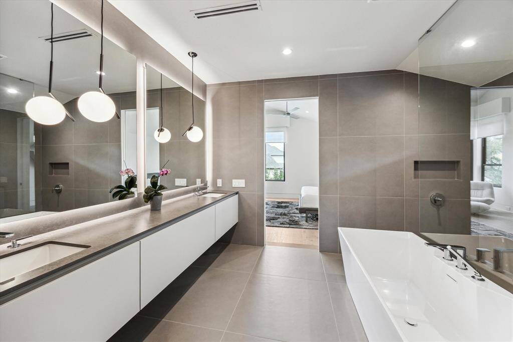 This bathroom connects to a bedroom-sized custom closet with built-ins from wall to wall, floor to ceiling, an island with drawers, and a makeup vanity.