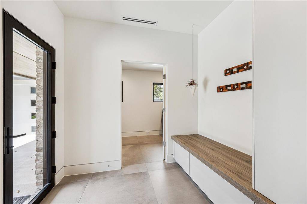Spacious MUD room features custom-built wall unit with storage/sitting area by LEICHT. The Laundry room is at the end and is very spacious with cabinets, a countertop, and a sink.
