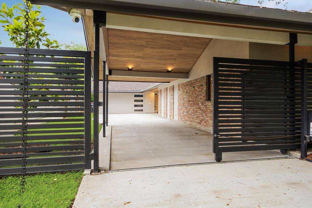 Contemporary gated Motor driveway entry with an extended covered and illuminated carport is ideal for privacy.