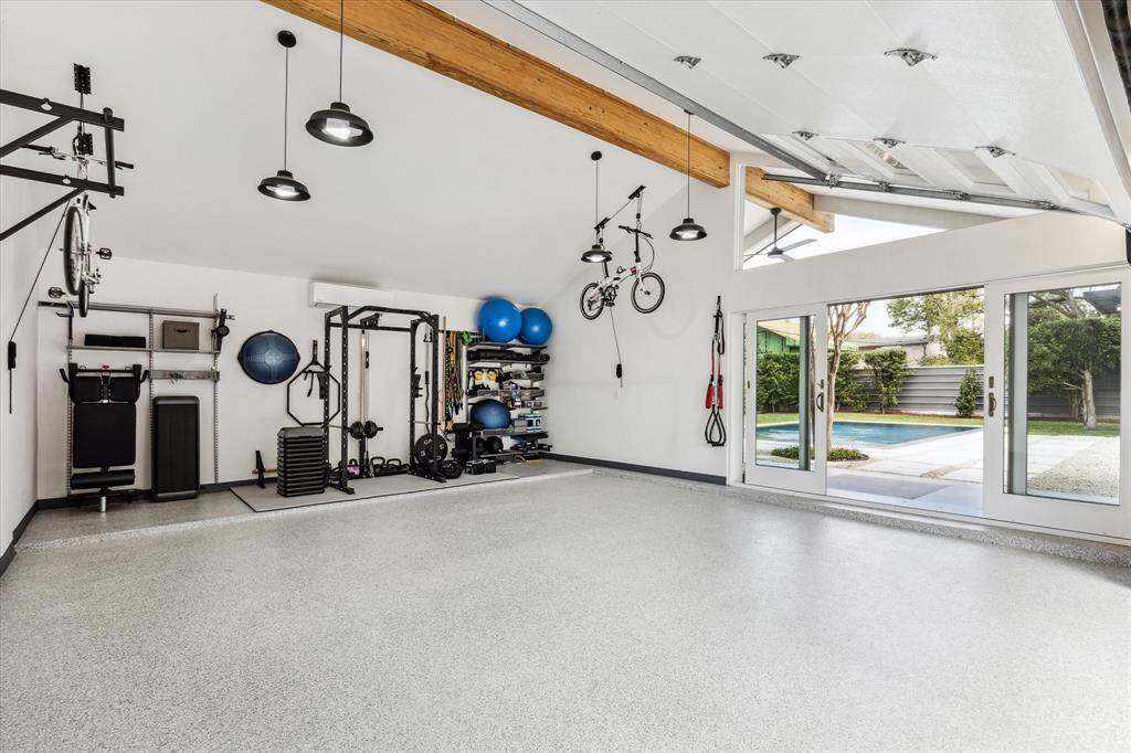 Two-car garage detached with high ceiling, split AC unit, epoxy flooring, and sliding side door with easy access to the cabana and pool area.