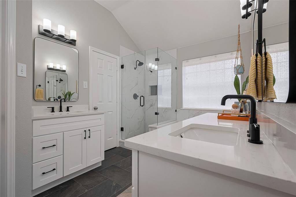 The Primary Bathroom features 12x24 Tile Floors and Shower Surround, Quartz Counters, Seamless Shower, Soaking Tub and Black Fixtures and Finishes.