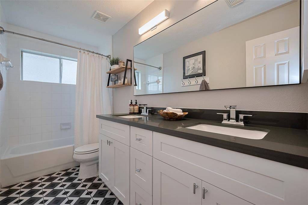 The Secondary Bathroom with Dual Raised Vanity, Quartz Counters, and Recent Tile Floors