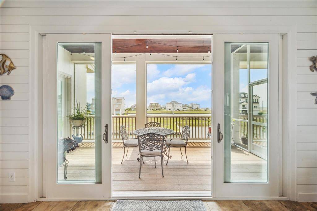 Wide, sliding glass doors open onto a sweeping patio that overlooks the water, allowing natural light to flood the open-concept living area.