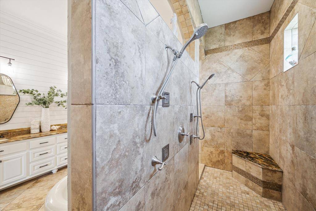 Expansive walk-through shower tucked under twin arched entryways.